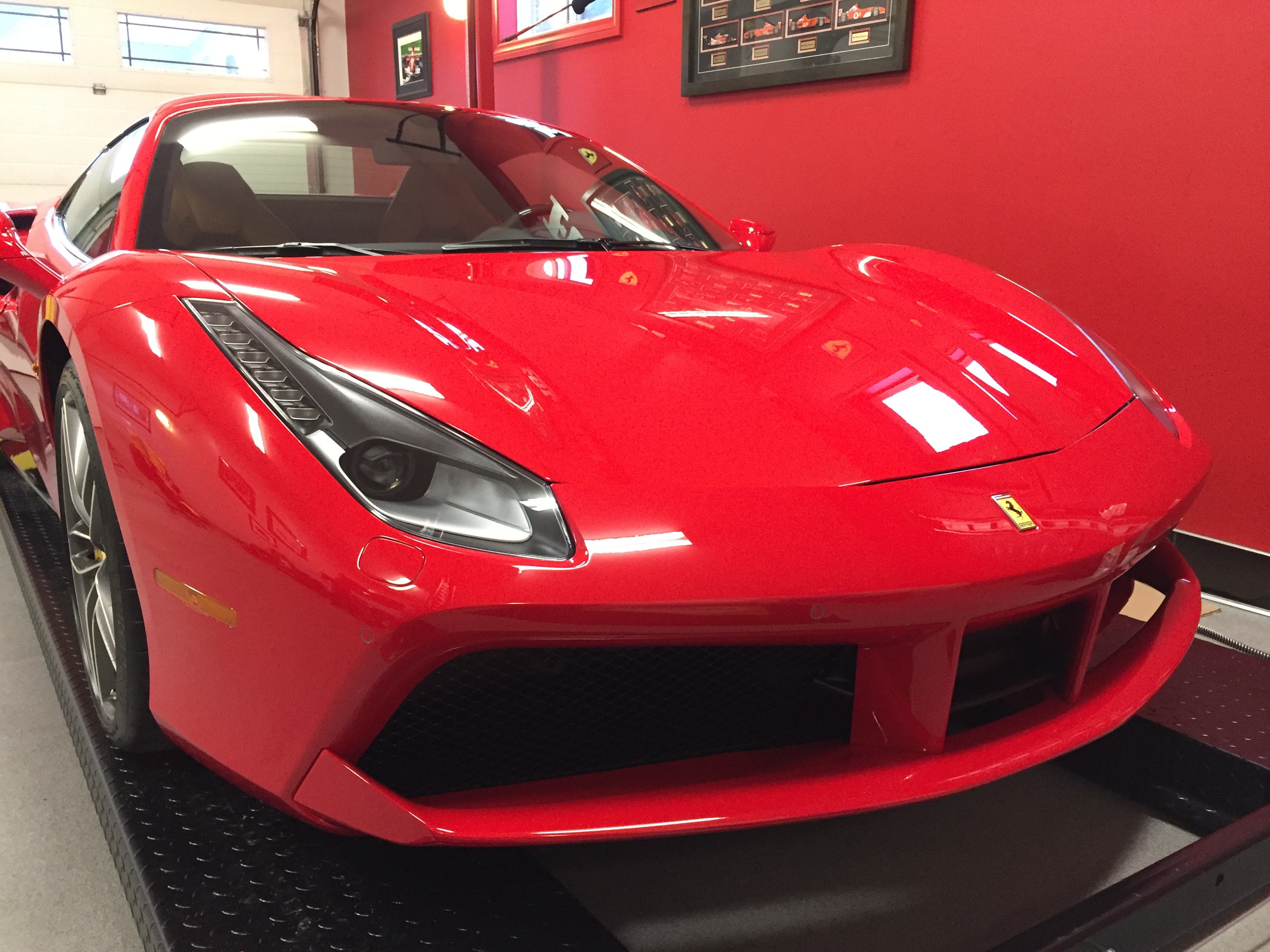 Finished red sports car in the Skyline Reflections shop after film work, showing tinted glass and clean paint reflections