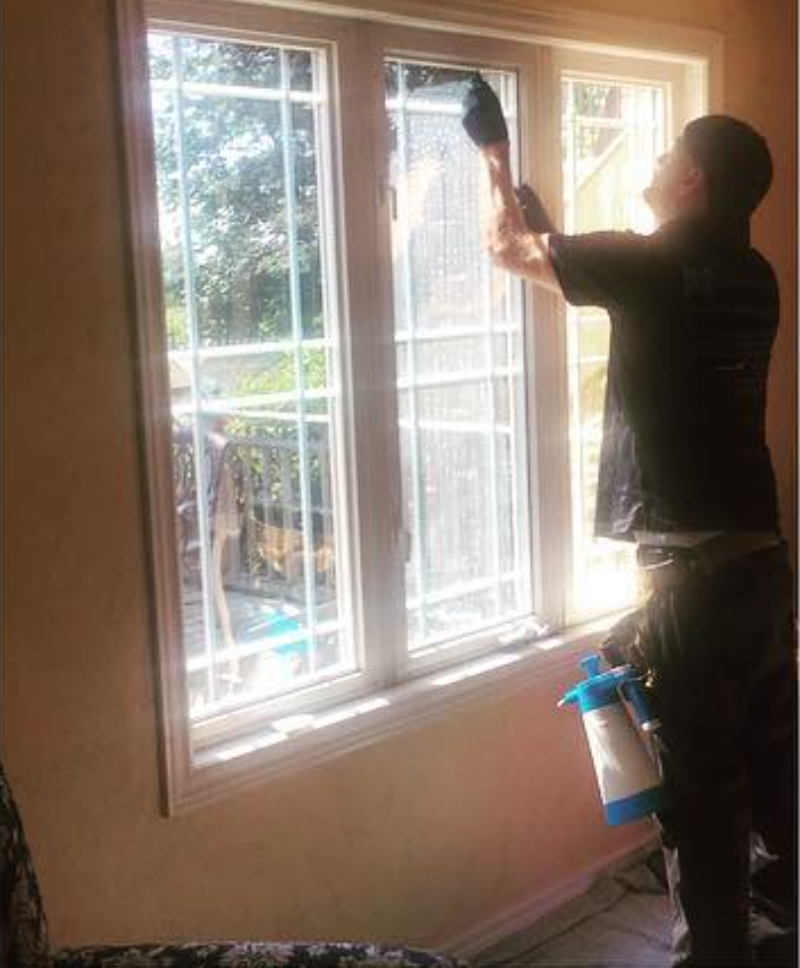 Skyline Reflections installer applying residential window film to a large window in a Hamilton-area home