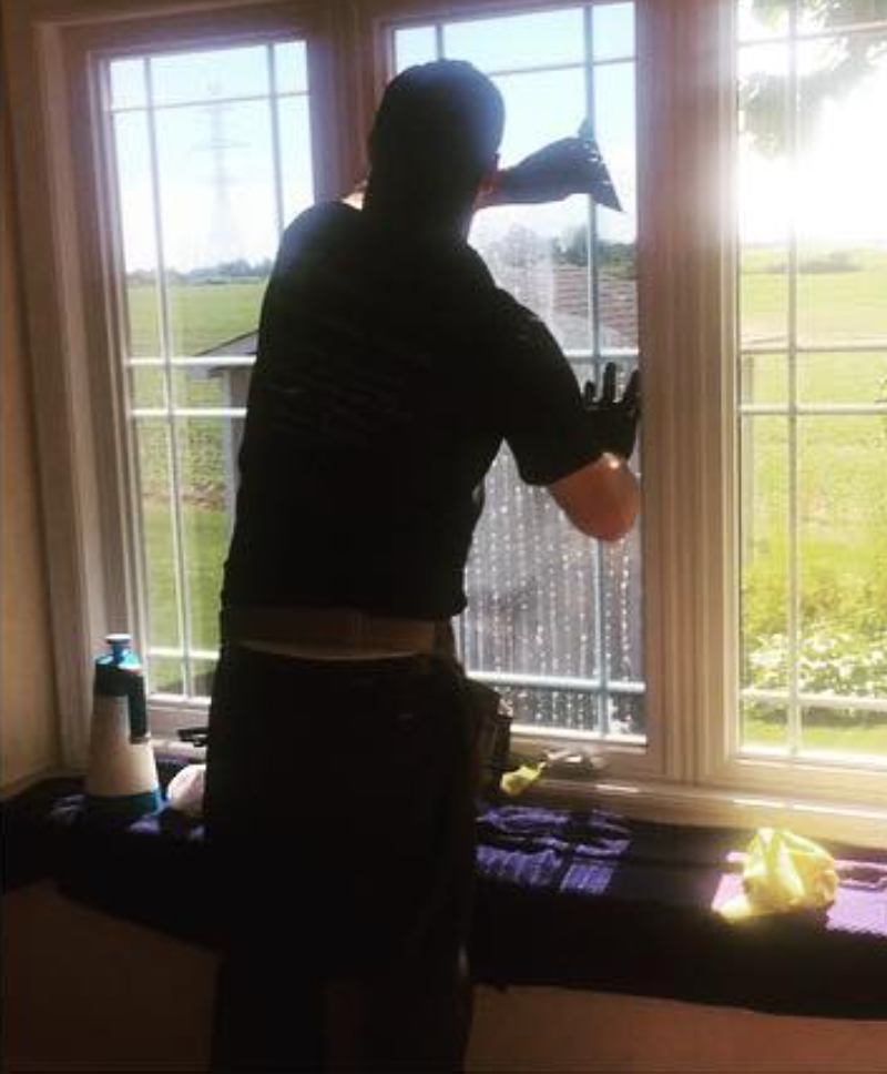Installer preparing and cleaning a residential window before applying window film